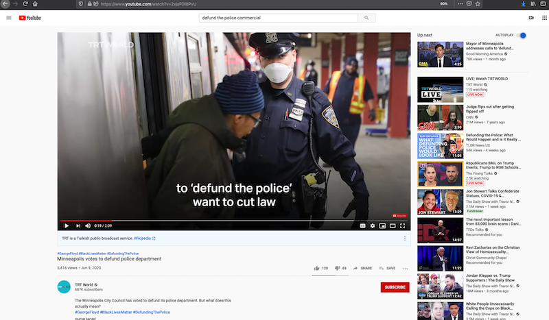 Screenshot of a topically relevant YouTube video, displaying the search term used to locate it ('defund the police commercial'), a still image from the video itself of a masked police officer and a civilian of color, with additional recommended YouTube videos visible on the side. Some user comments are also visible underneath the video window, which illustrates the discussion platform available on YouTube